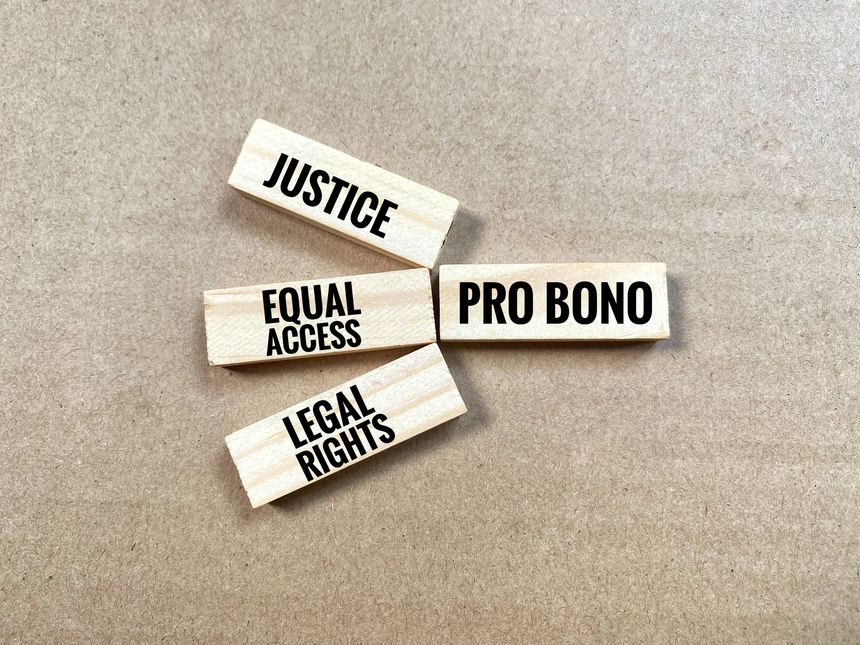 Wooden block labeled Pro Bono is connected to three other blocks that read Justice, Equal Access, and Legal Rights.