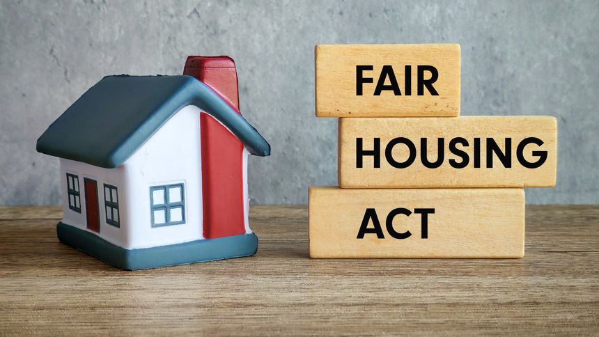 Fair Housing Act Text with Miniature House on Wooden Table and Gray Background