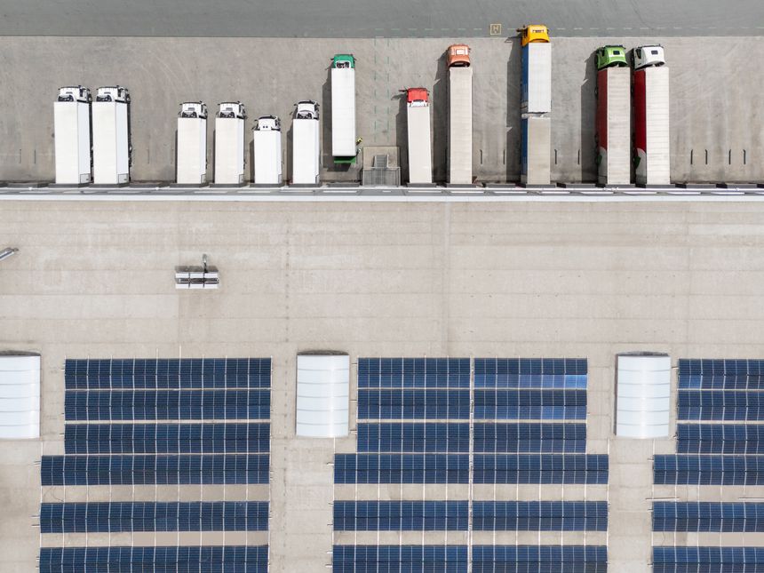 Logistic center with solar panels on roof. Aerial view. Drone point of view.