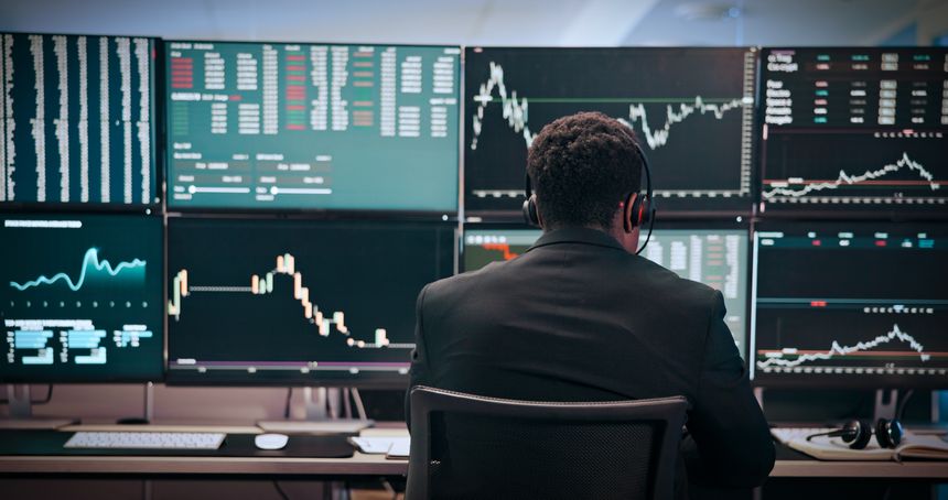 Businessman, trading and monitor with headset at office for stats, graphs and night with stock market investing. African person, broker and trader with voip with back, charts or screen at agency