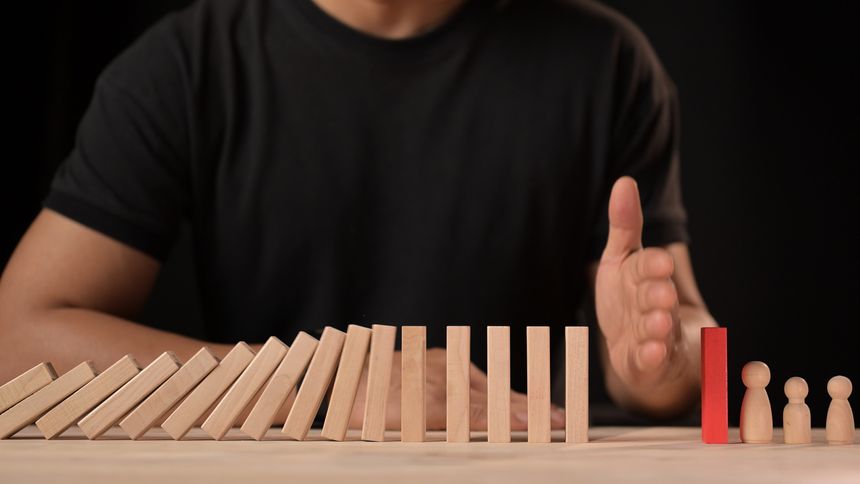 Hand stopping falling dominos navigating business crisis decision making in risk management leadership and strategic planning