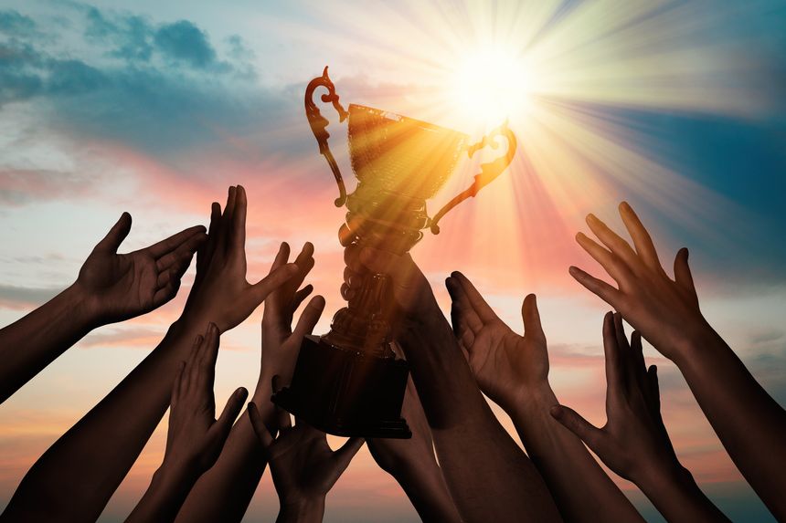 People reaching for a trophy against a sunset. For motivational business campaigns, team achievement awards, and corporate success celebrations. Inspires aspiration, recognition, and teamwork.