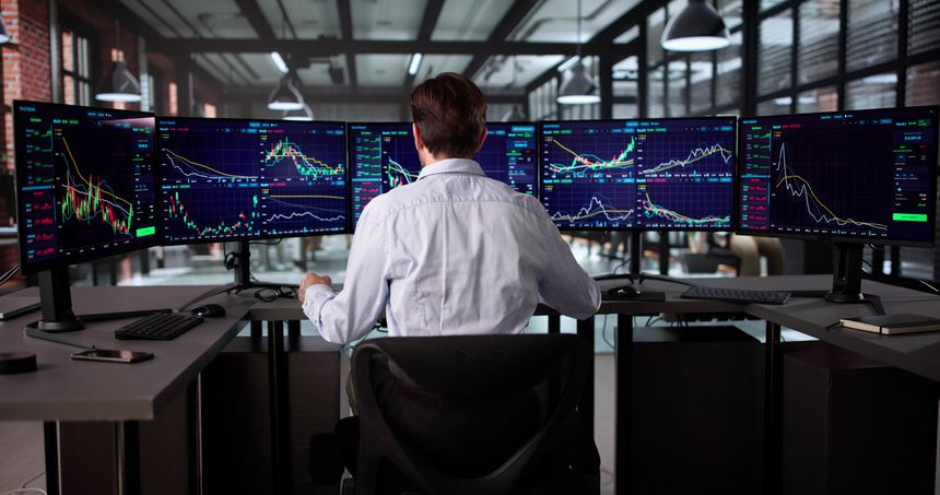 Senior Broker Analyzing Stock Market Data On Multiple Computer Screens.
