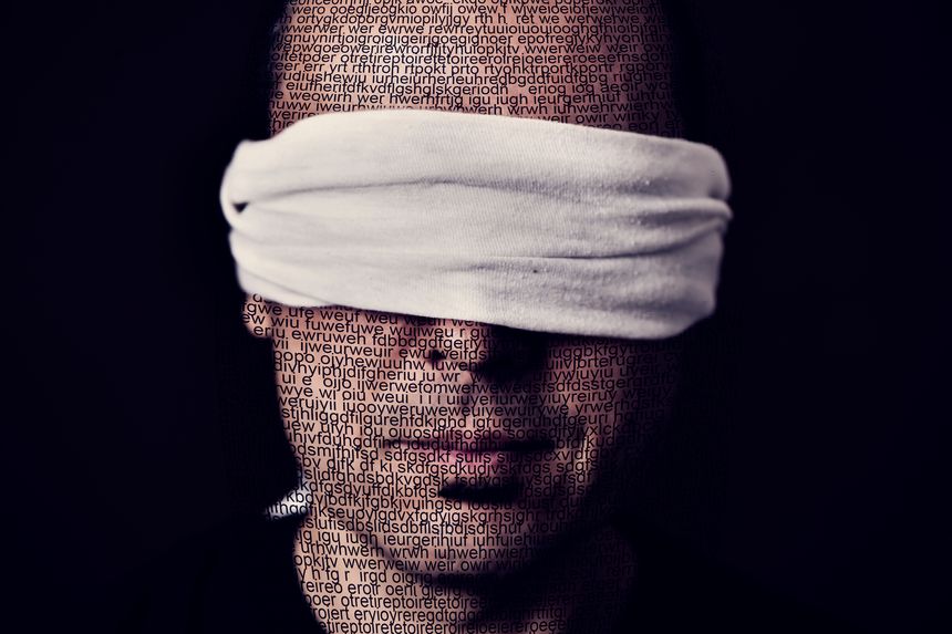closeup of a young man patterned with no-sense words with a blindfold in his eyes, depicting the idea of lack of press freedom