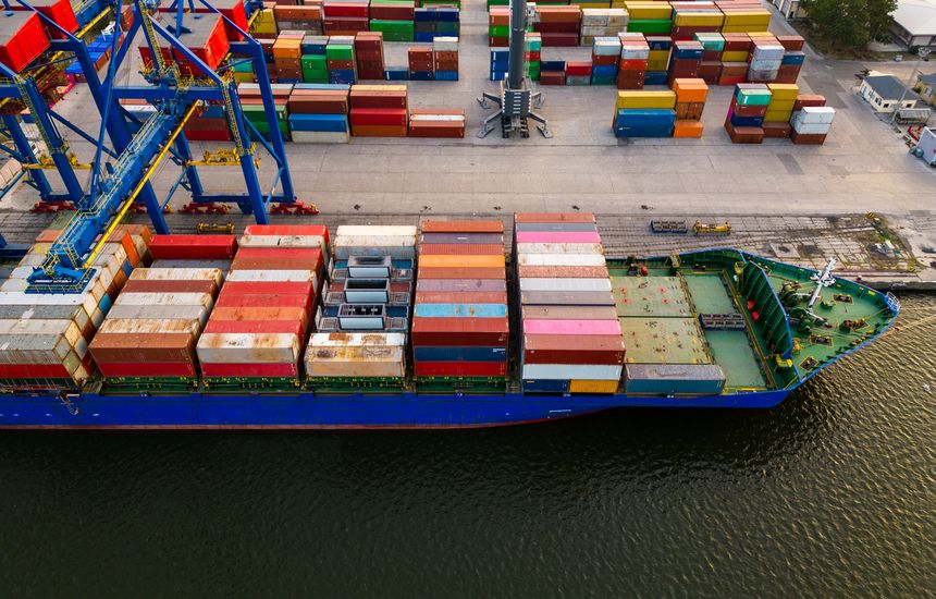 aerial top down view of a container ship in terminal at the port, where massive containers await their journey