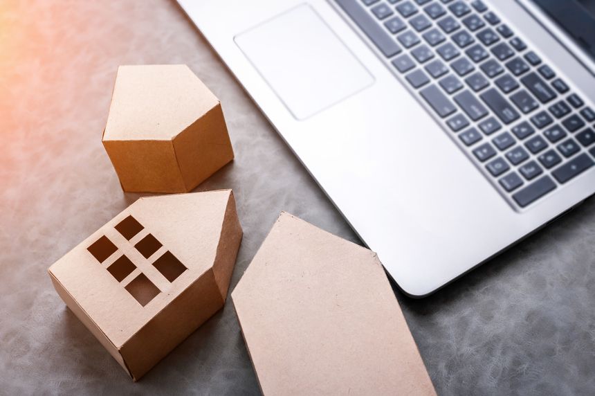 laptop with house in brown recycled paper on grey leather background with free copy space for your text ideas house concept