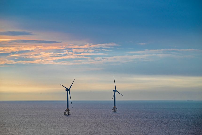 Two big wind turbines are standing in the sea.