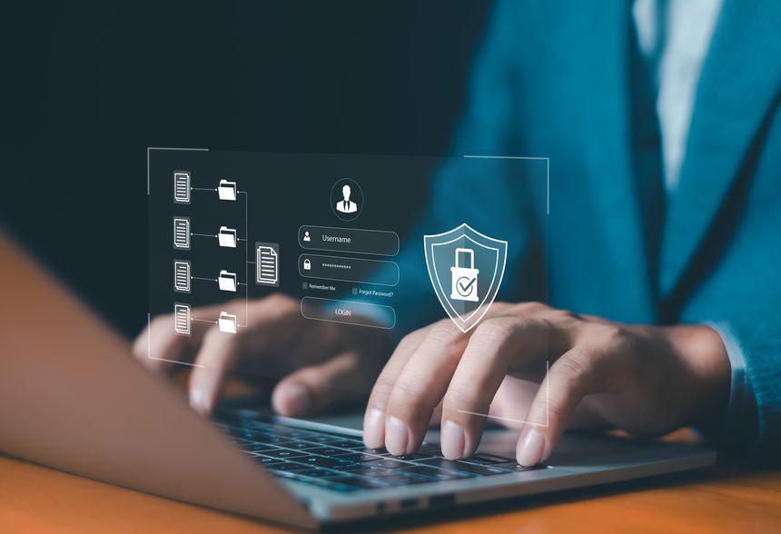 Businessman using laptop with digital login and file security interface, representing cybersecurity, data protection, secure access, online privacy and secure file management technology.