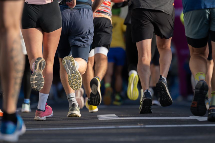 close up of diverse marathon runners feet in athletic shoes running on city pavement in Ljubljana urban marathon event on sunny day