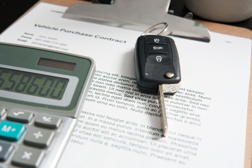 Car keys lying on a vehicle purchase contract, suggesting a finalized car purchase agreement