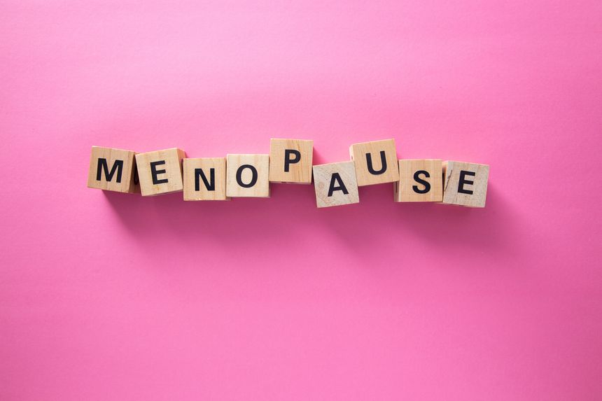 Menopause concept with wooden cubes forming the word on a pink background