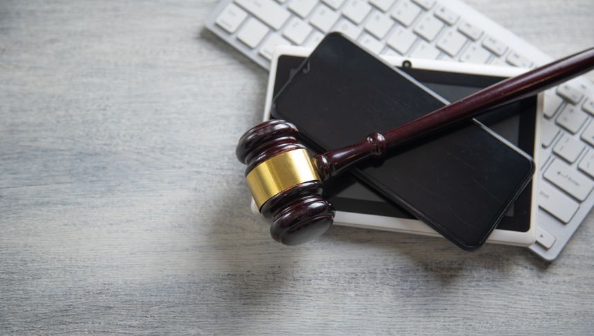 Judge gavel with a phone, tablet, computer keyboard.