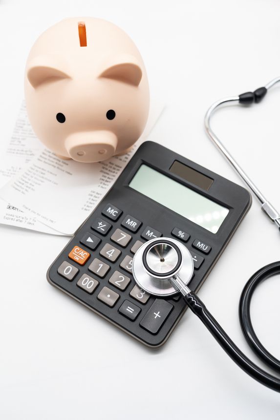 Piggy bank, calculator, and stethoscope with medical bills, symbolizing healthcare expenses, medical cost management, and financial planning. Health insurance, hospital billing, and medical cost.