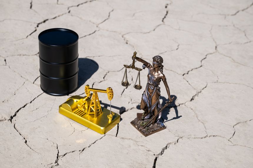 A figure of Themis and a miniature golden oil pump on heat-cracked clay in the desert