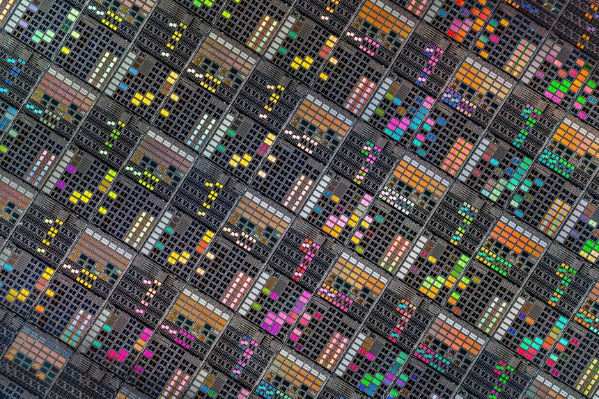 Detailed view of patterned silicon semiconductor wafer showing many integrated circuit dies in a geometric grid, colorful electronic texture for chip manufacturing and technology themes.