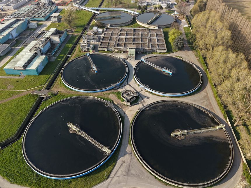 Aerial view of a water treatment plant in Peschiera Borromeo, Milan, with large wastewater tanks and biogas energy systems, showcasing sustainable development.
