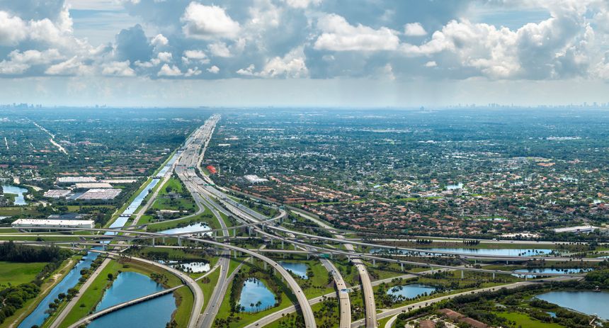 View from above of USA transportation infrastructure. American freeway intersection with fast driving cars and trucks in Miami, Florida.