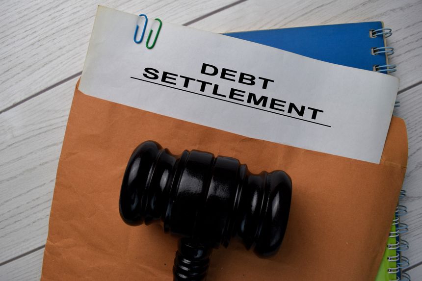 Debt Settlement text with document brown envelope and gavel isolated on office desk.