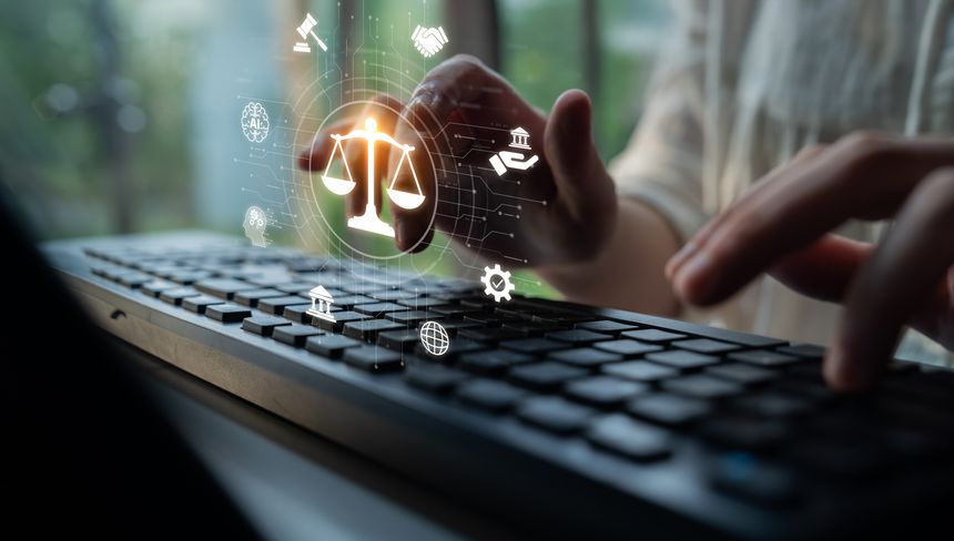 Close-up of hands typing on a keyboard with digital symbols representing justice and law, highlighting the intersection of technology and legal practice in a contemporary setting.