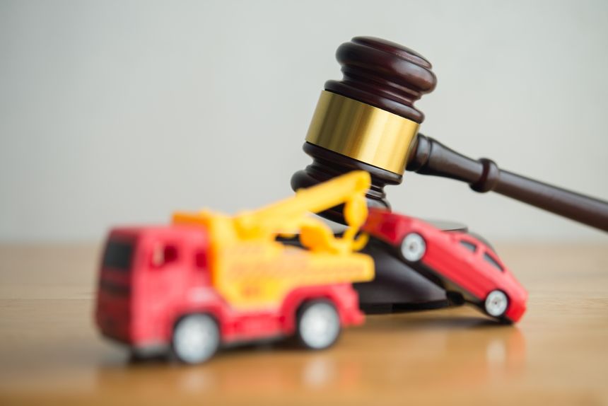 Hammer judge gavel and tow truck with car on wooden table white wall background copy space. Vehicle repossession law, bankruptcy, personal financial problem and so on concept.