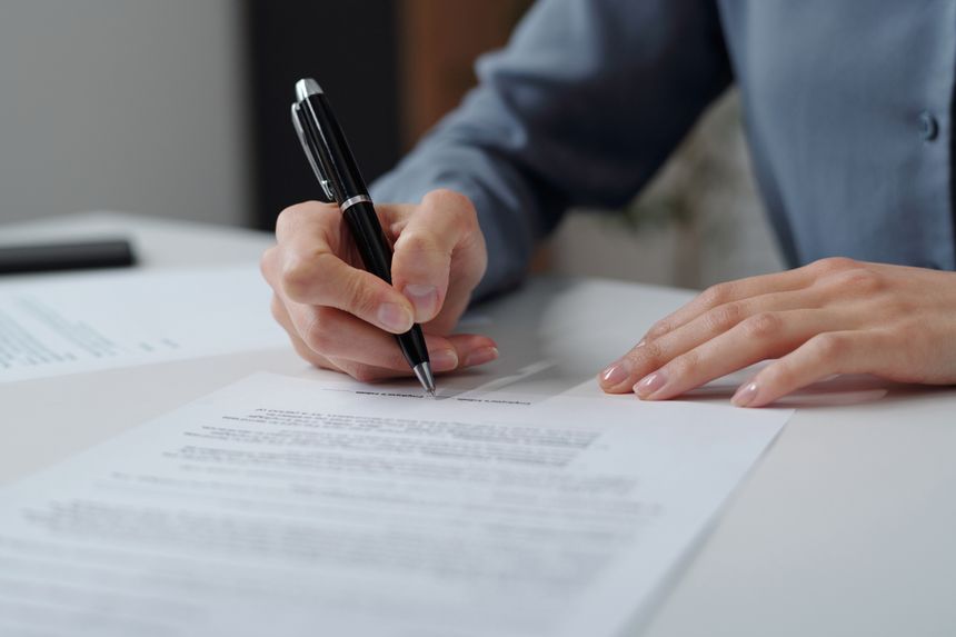 Closeup of unrecognizable businesswoman signing contract in osffice with focus on female hand holding pen copy space