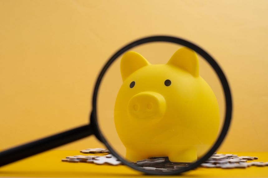 Yellow piggy bank with magnifying glass and puzzles. Financial planning and investment strategy concept.