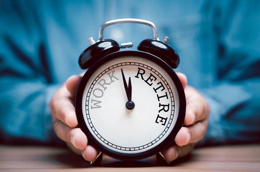 Businessman holding black alarm clock with clockwise countdown from work to retirement.