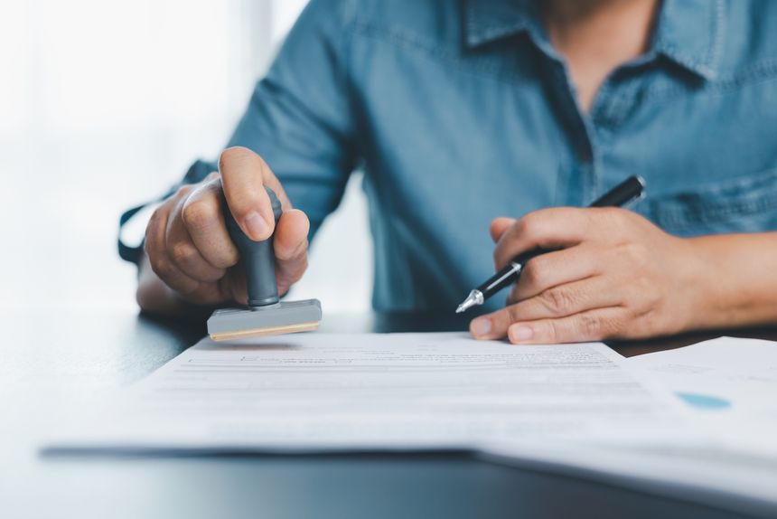 Businessman hands stamp approve on financial business approval document paper. Man hand accepted permit contract agreement. Broker manager sign contract bank guarantee approved stamp application form