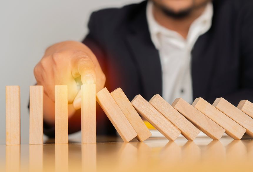 Close-up the hand of a businessman who is stopping or preventing a falling block. Risk protection concept, Eliminating the risk.
