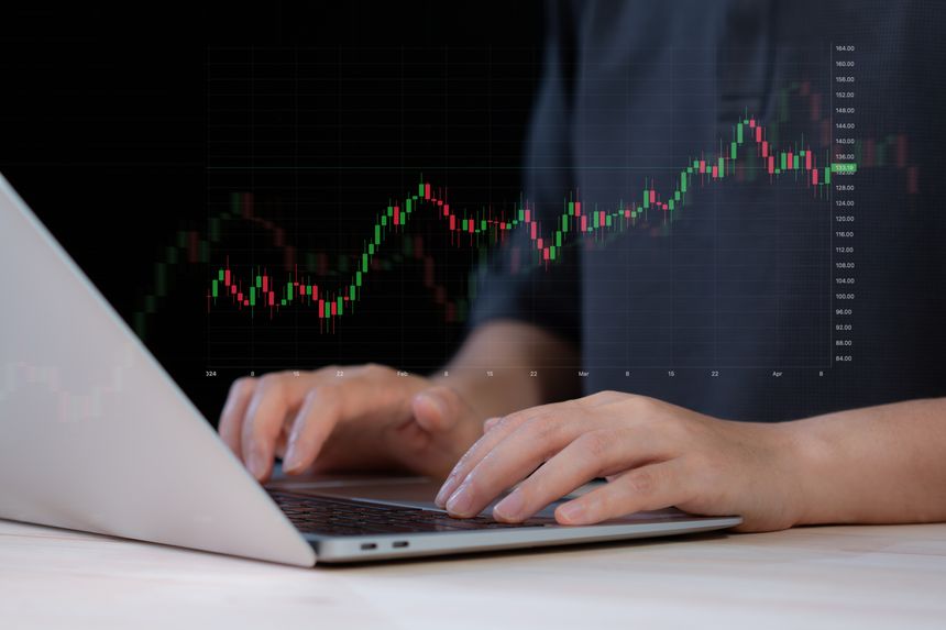 Businessman using laptop with 3D floating candlestick chart. Financial trading, stock market and investment concept