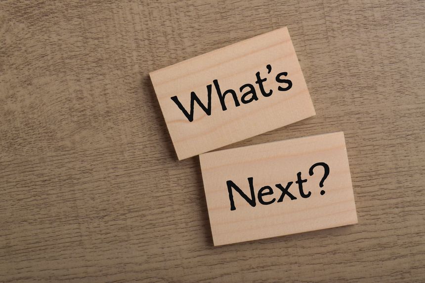 What's next concept featuring two wooden blocks with question text on a wooden background, representing uncertainty, planning, decisions, and future possibilities.