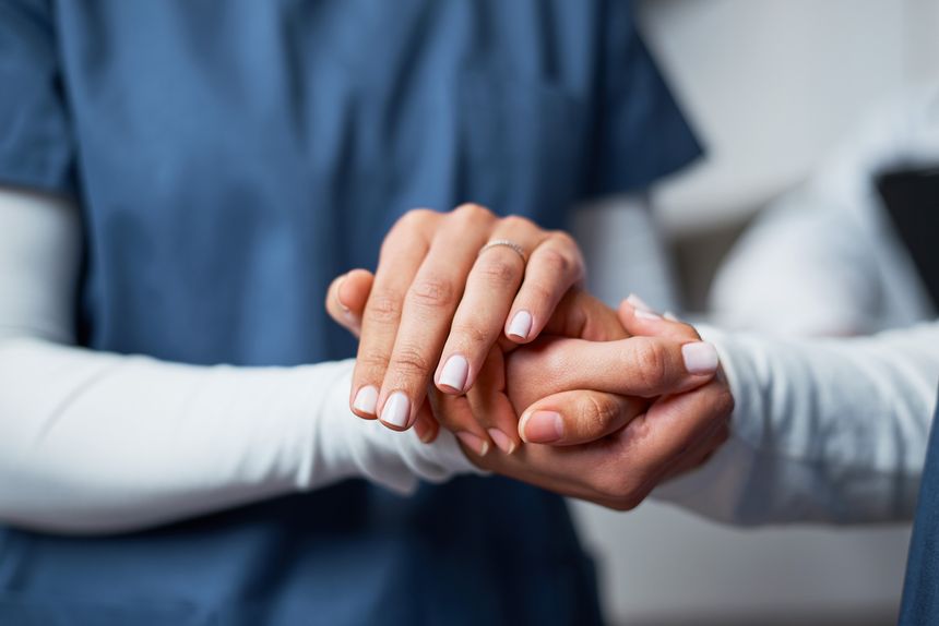 A professional nurse provides emotional support by gently holding a patient's hand, symbolizing care and empathy. This closeup image communicates trust, kindness, and the human connection within the medical field.