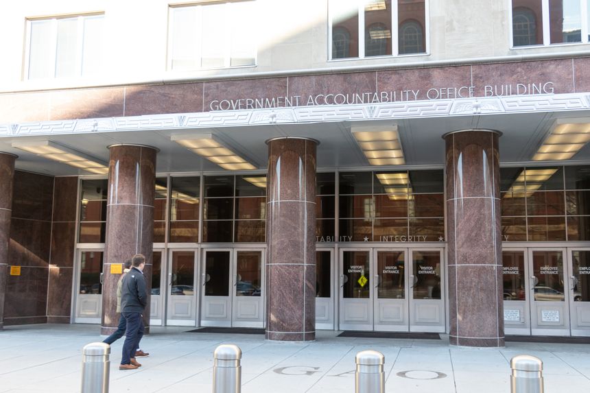 People walk towards the main entrance to the Government Accountability Office Building.