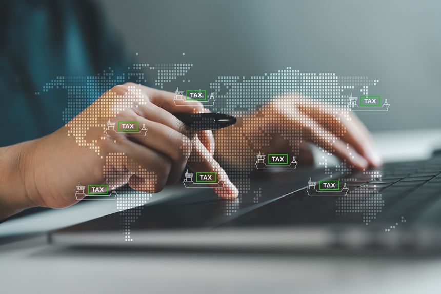 Business Hands using digital tablet with stylized world map overlay and icons of cargo ships labeled TAX. Concept of global import export tax, customs duties or international trade compliance.