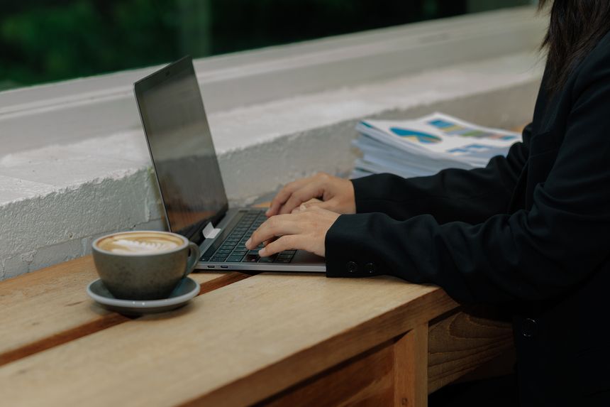 Young professional woman in an office, focused on detailed data entry while examining physical files, highlighting self-discipline and career success.