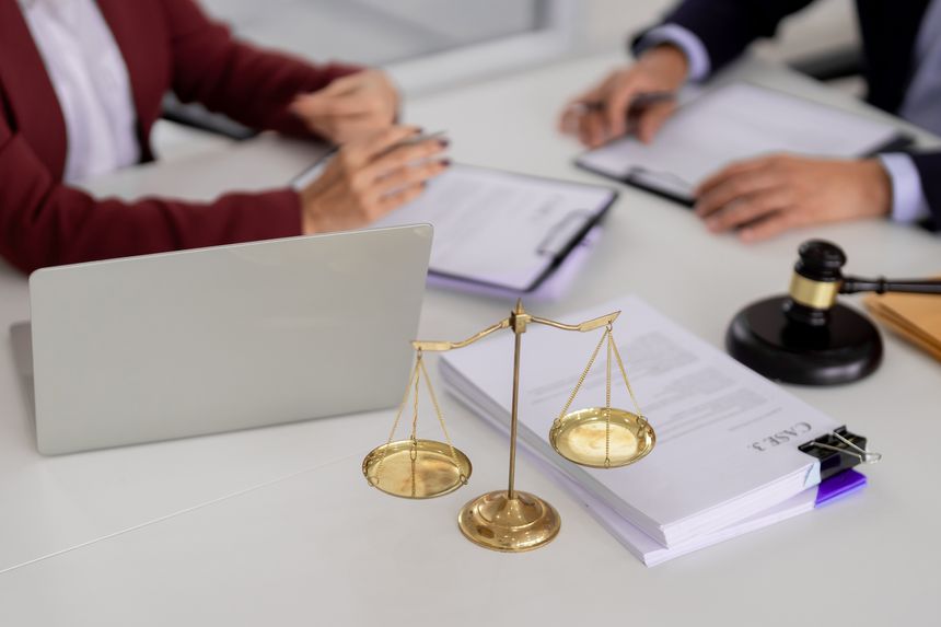 Adult male female hands reviewing legal paperwork in a professional office. Justice symbols technology aid advice and discussion