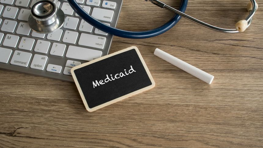 Medicaid text on blackboard sign next to computer keyboard and stethoscope for government health insurance and social security concept