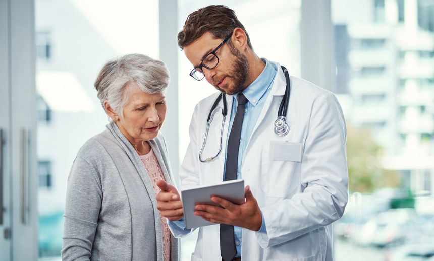 Shot of a doctor discussing something on a digital tablet with a senior patient in a clinic