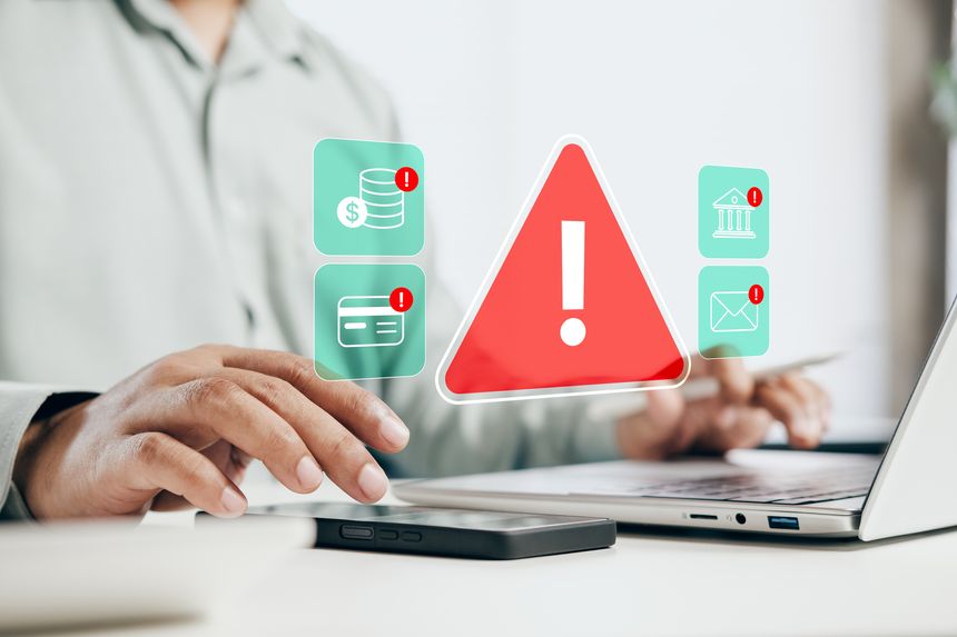 Business professional receiving cybersecurity risk alerts on laptop and smartphone, fraud detection, financial security monitoring, data protection warnings, digital threat management, modern banking