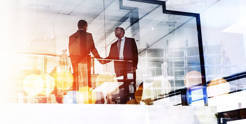Shot of two businessmen shaking hands superimposed over a cityscape