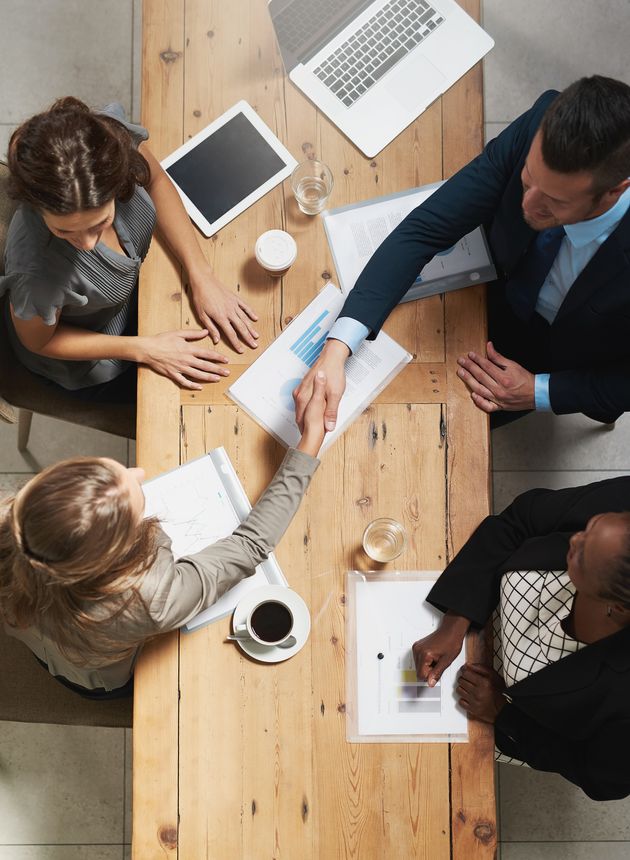 High angle shot of a group of businesspeople shaking hands during a meeting in an office