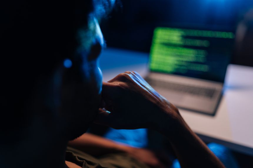 Pensive developer writing code late at night, working on programming software, debugging system issues, ensuring cyber security protection during dark room session, close-up back view.