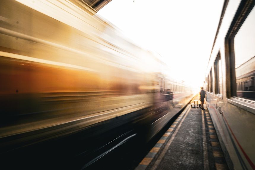 A train passing a station platform at high speed, creating a significant motion blur effect. Business concept of fast growth, success and momentum.
