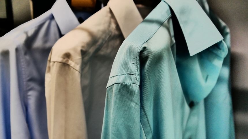 Three men's shirts hanging inside a wardrobe close-up