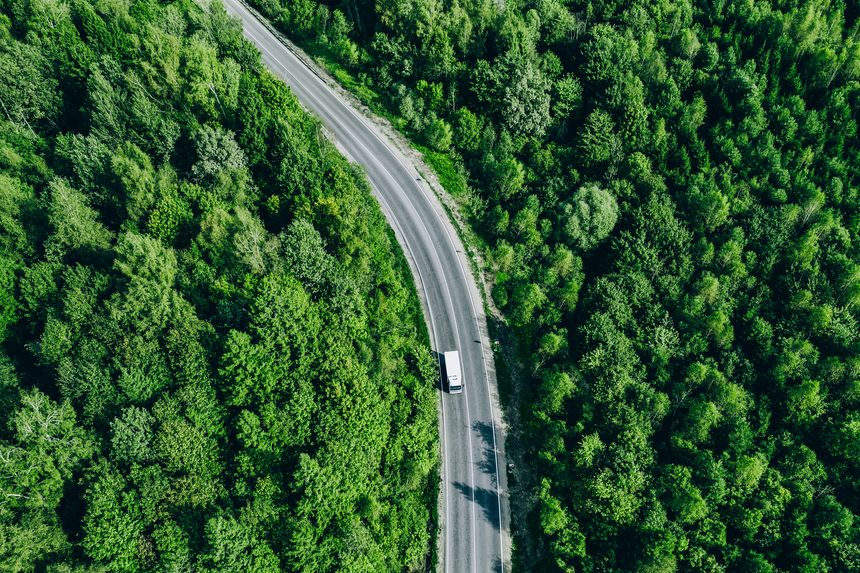 Aerial drone view of truck car on green summer curved road. Transportation and logistics concept