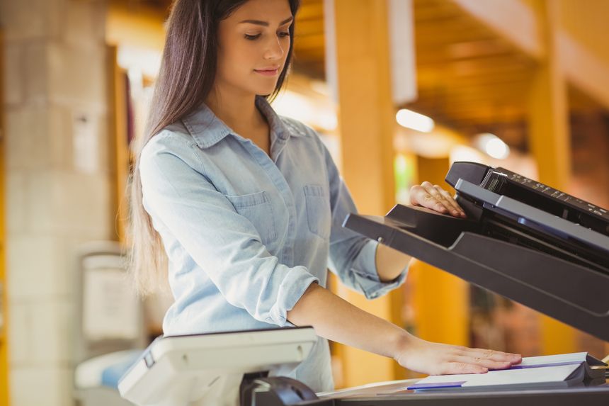 Smiling brunette student making a copy in library