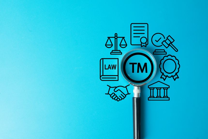 Trademark and intellectual property law concept. A magnifying glass focuses on the TM symbol, surrounded by icons of justice, contracts, and regulations for brand name and logo protection.