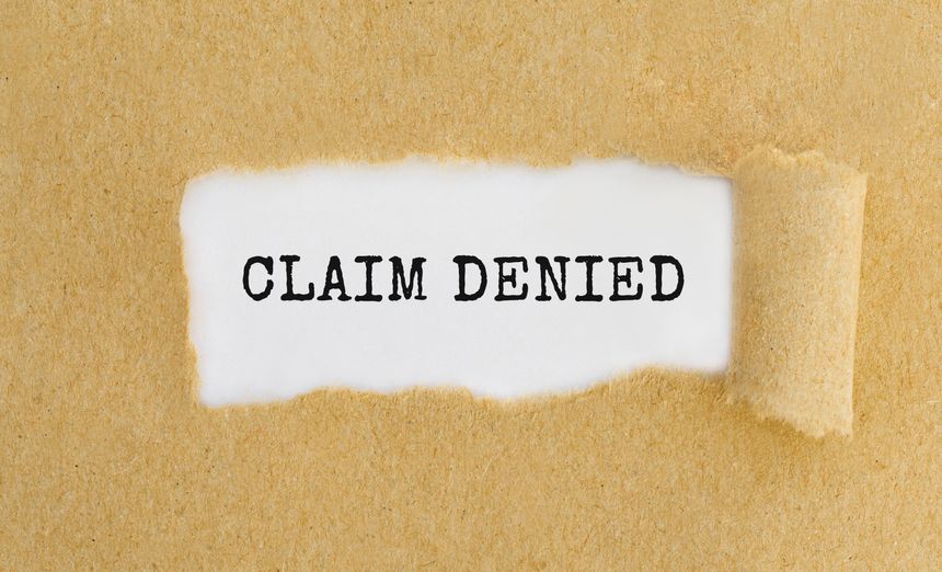 Text Claim Denied appearing behind ripped brown paper
