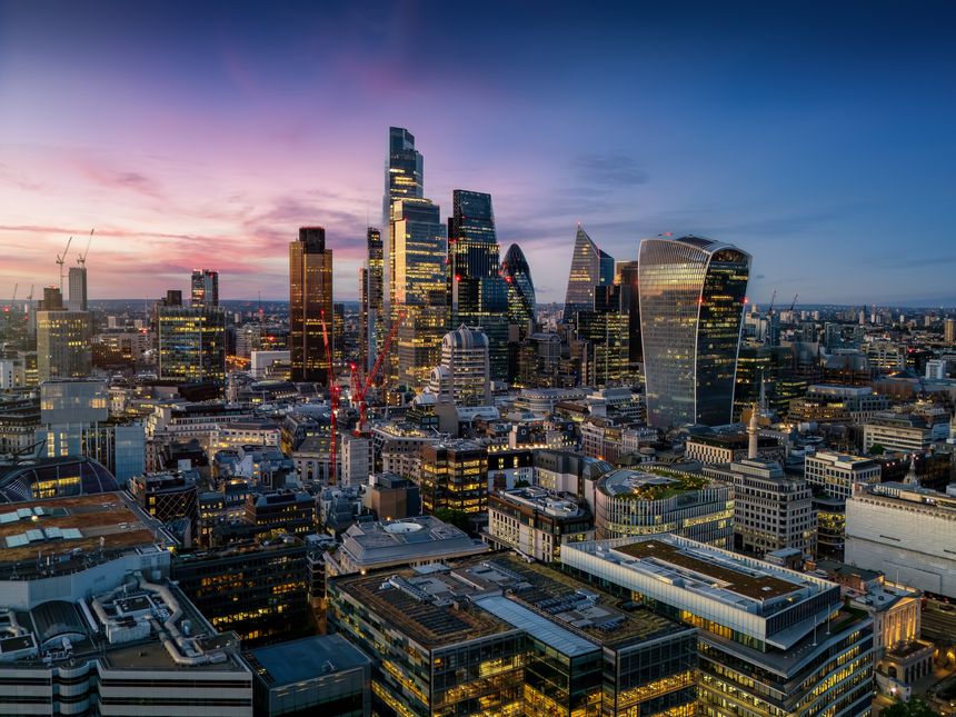 Aerial view of the illuminated skyscrapers at the City of London, England, during evening time with a colourful sky