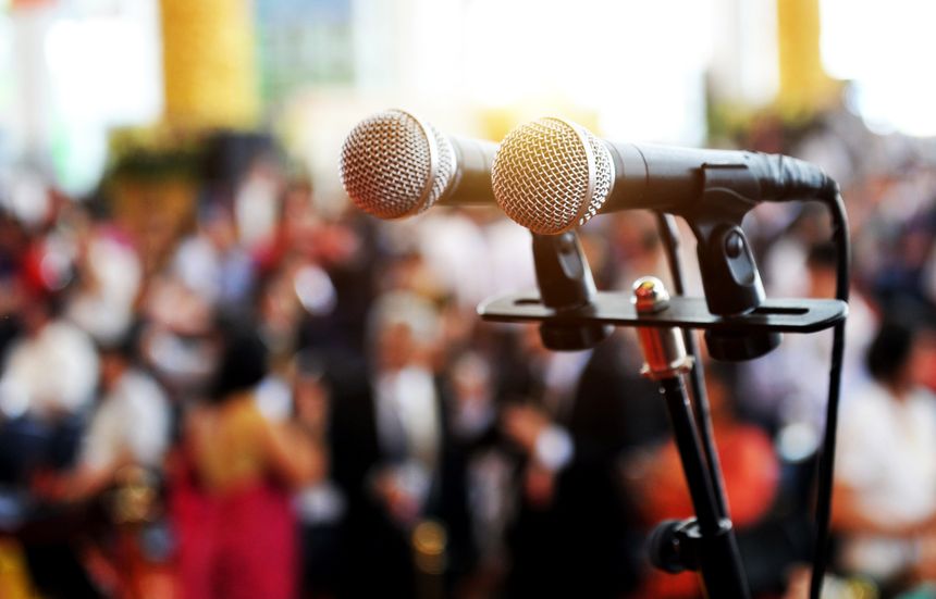 Closeup microphone in auditorium with people.